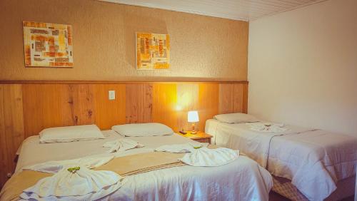 a room with two beds with towels on them at Pousada Atalaia Capivari in Campos do Jordão