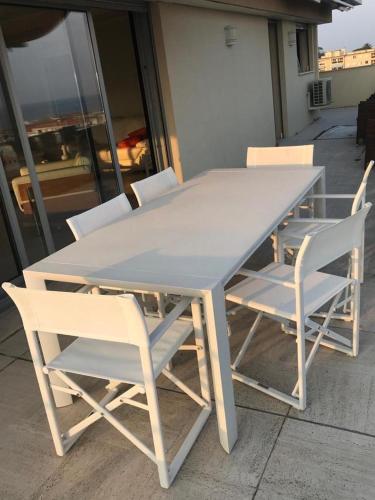 une table blanche et des chaises assises sur une terrasse dans l'établissement cannes seaview penthouse, à Cannes