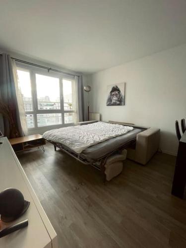 une chambre avec un lit et une grande fenêtre dans l'établissement Skyview appartement la Défense, à Courbevoie