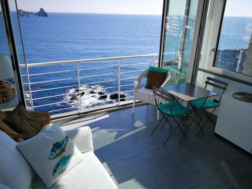 a balcony of a cruise ship with a table and chairs at The sea you can feel in Aci Castello