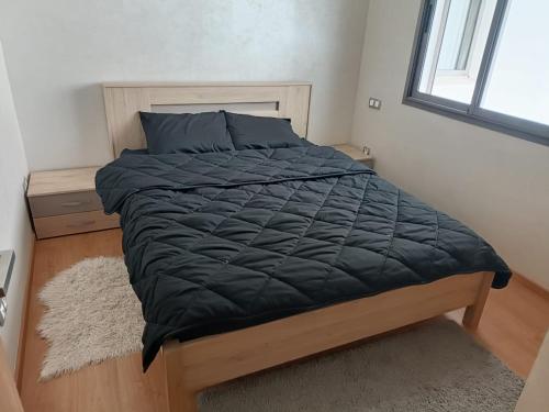 1 cama con edredón negro en un dormitorio en Appartement au Parc Mohammedia, en Mohammedia
