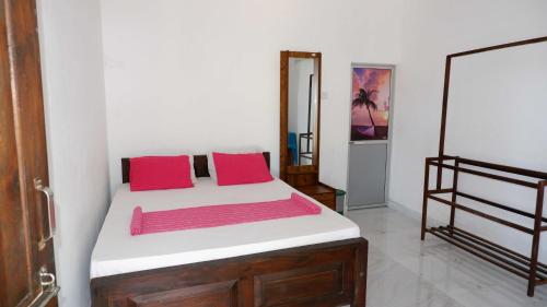 1 dormitorio con 1 cama con 2 almohadas rojas en Attale Resort, en Hambantota