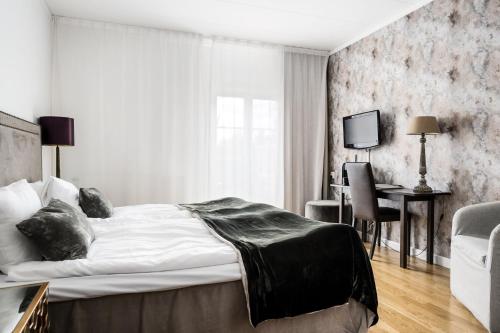 a bedroom with a large bed and a desk and a table at Körunda Golf & Conference Hotel in Ösmo
