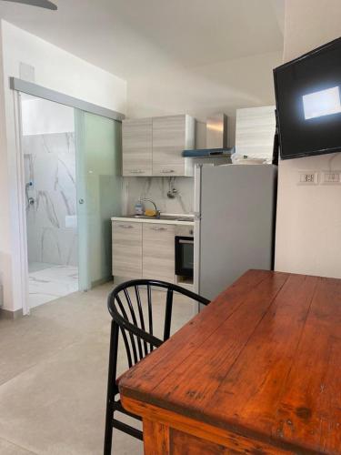 a kitchen with a wooden table and a refrigerator at Lido Di Alghero Rooms on the Beach in Alghero
