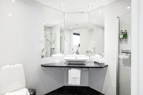 La salle de bains blanche est pourvue d'un lavabo et de miroirs. dans l'établissement Körunda Golf & Conference Hotel, à Ösmo