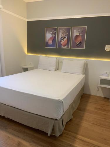 a bedroom with a large white bed with four pictures on the wall at Ninety Hotel in São Paulo