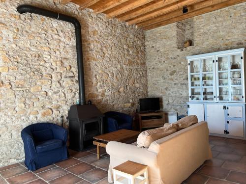 a living room with a stone wall with a couch and a stove at Le Clos Sainte Marie - Caune in Cenne-Monestiès