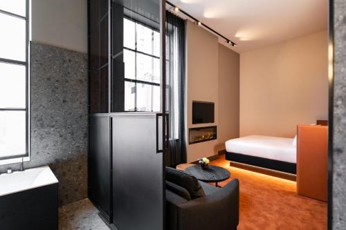 a small room with a bedroom with a bed and a couch at Van der Valk TheaterHotel De Oranjerie in Roermond