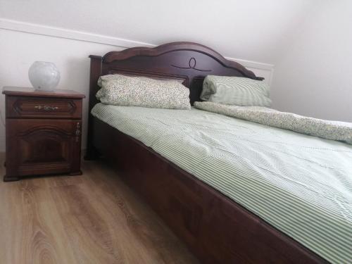 a bed with a wooden headboard next to a night stand at Ikerdió faházikó in Szarvas