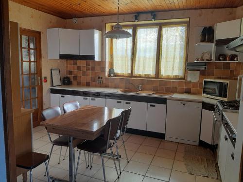 Il comprend une cuisine avec une table et des chaises en bois. dans l'établissement En Auvergne au cœur du parc Livradois Forez, à Cunlhat