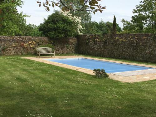 a bench sitting in the grass next to a swimming pool at Manoir des Bords de Rance in Plouër-sur-Rance