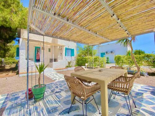 a patio with a table and chairs under a pergola at Unique Cycladic Detached House - Private Garden - Helena in Análipsis