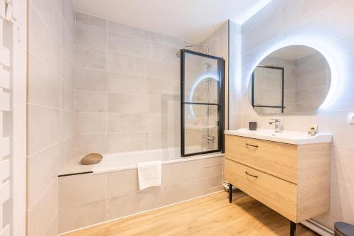 een badkamer met een wastafel, een bad en een spiegel bij Le jardin d'hiver in Pontoise