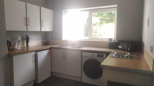 a kitchen with a washing machine and a window at The Old White Hart Brewery Guesthouse in Bath