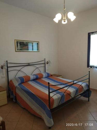 a bedroom with a bed with an orange and blue striped blanket at Acquadolce in San Teodoro