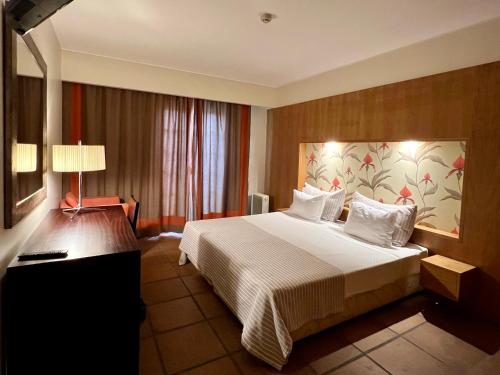 a hotel room with a large bed and a lamp at Apartamentos Turisticos Atlantida in Funchal