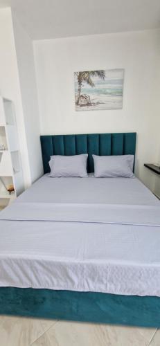 a bed with white sheets and a green head board at Oasis in Durrës