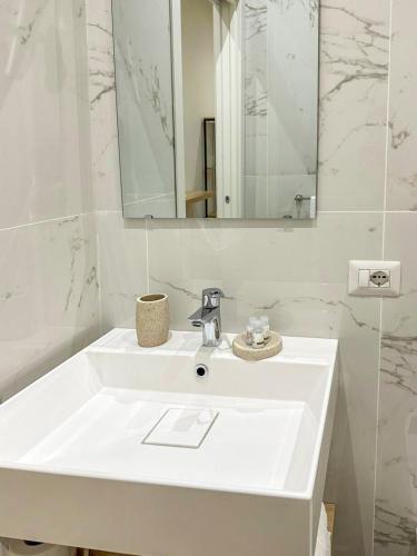 a white bathroom with a sink and a mirror at CasaMarì in Torre del Greco