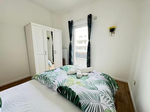 Schlafzimmer mit einem Bett mit einer grünen und weißen Bettdecke in der Unterkunft Odyssée - Appartement neuf Cergy in Cergy