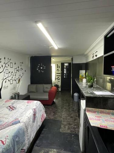a bedroom with a bed and a couch and a kitchen at Bachelor Pad Rondebosch Self Catering in Cape Town