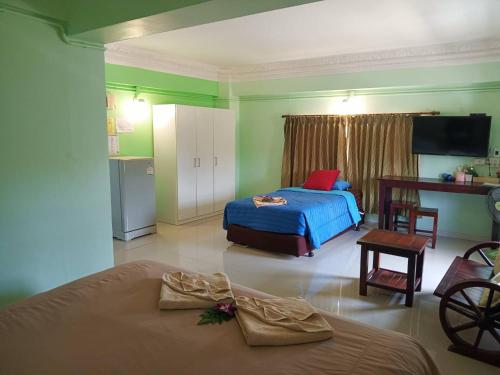 a bedroom with a bed and a table and a tv at Anchalee Resort in Bang Saphan