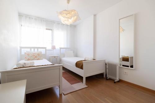 a white bedroom with two beds and a mirror at Akicity Jamor Selected in Cruz Quebrada