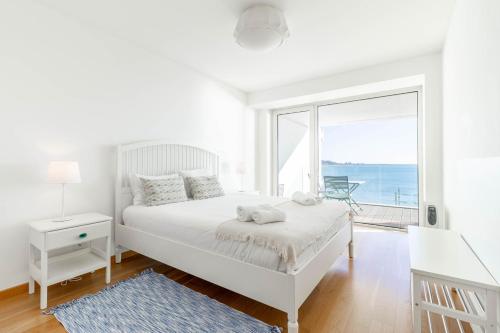 a white bedroom with a bed and a large window at Akicity Jamor Selected in Cruz Quebrada