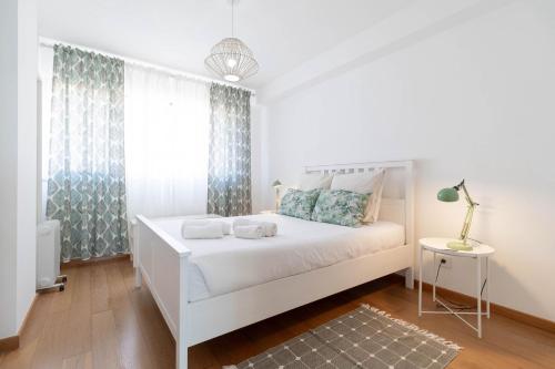 a white bedroom with a white bed and a window at Akicity Jamor Selected in Cruz Quebrada