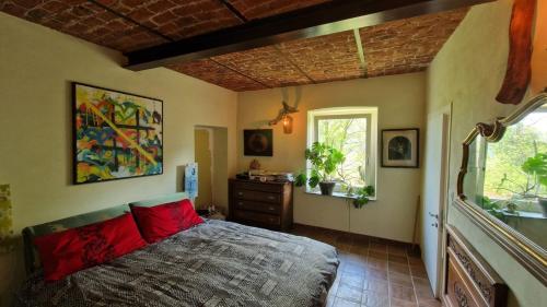 a bedroom with a bed with red pillows and a window at Villa Aurora Sotto Le Stelle in Torre Pellice