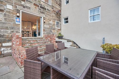 a patio with a table and chairs and a building at Pecks Cottage in Whitby