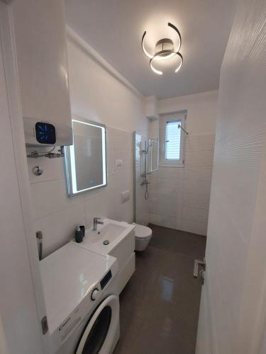 a white bathroom with a sink and a toilet at Apartman Lana in Rijeka