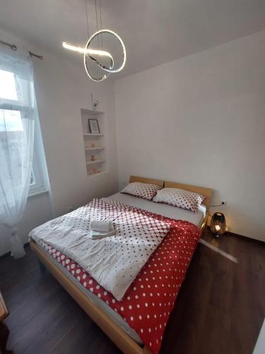 a bedroom with a bed with a red and white comforter at Apartman Lana in Rijeka