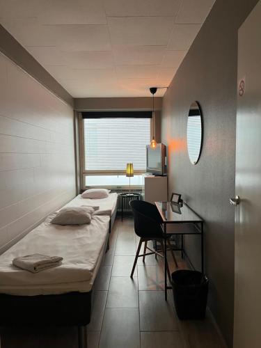a room with two beds and a desk and a mirror at Bella Hostel in Turku
