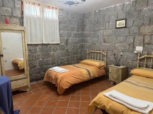 a bedroom with two beds and a stone wall at Cordel in La Serrada