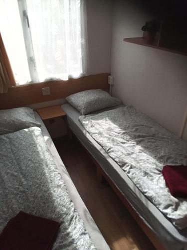 2 Betten in einem kleinen Zimmer mit Fenster in der Unterkunft Mobilní dům Venda in Hradišťko