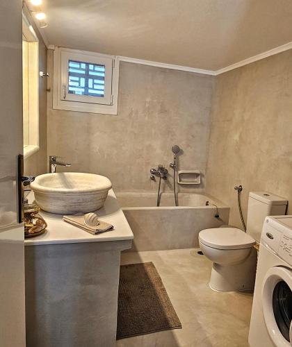 a bathroom with a tub and a sink and a toilet at Tinoshomelidays Residences in Venardatos