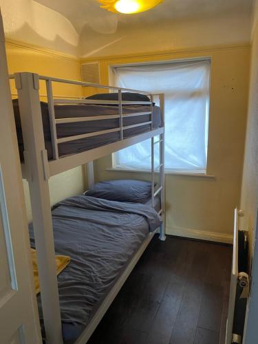 a bunk bed in a small room with a window at 2 Bed Flat near Heathrow Airport & Elizabeth Line in Hayes