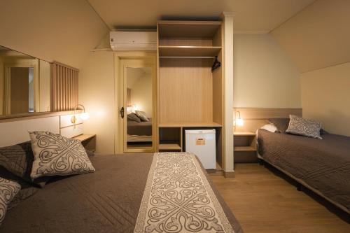 um pequeno quarto com 2 camas e um espelho em Hotel Cabanas Alto Da Serra em Canela