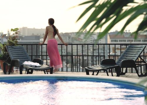 a woman standing on a balcony overlooking a swimming pool at Aparthotel VIP Executive Suites do Marquês in Lisbon