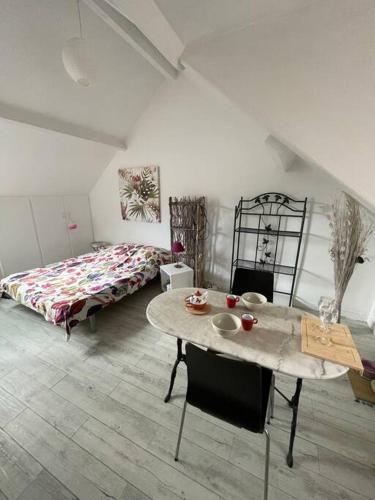 une pièce avec une table et un lit et une table et des chaises dans l'établissement Le Cocon rouge - studio en plein centre historique, à Lamballe