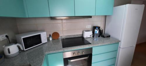 a kitchen with blue cabinets and a stove and a microwave at Casa Esmar in Odemira