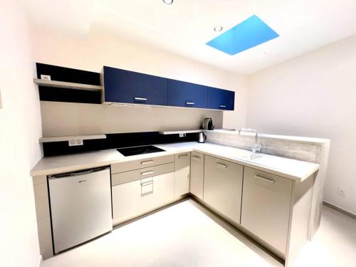- une cuisine blanche avec des placards bleus et un évier dans l'établissement Just renovated 3 bedrooms apt with AC 1300 sq ft, à Paris
