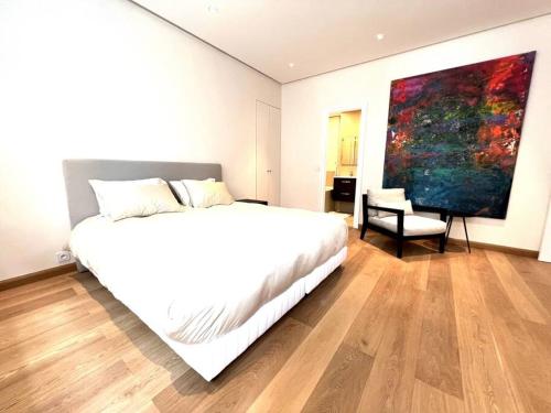 une chambre avec un lit blanc et un tableau au mur dans l'établissement Just renovated 3 bedrooms apt with AC 1300 sq ft, à Paris