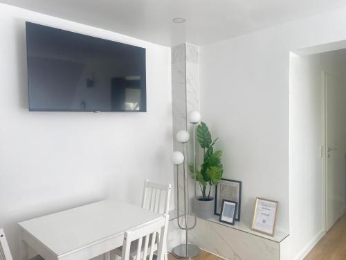 a white dining room with a table and a tv on the wall at Lux Apartment near Frankfurt! in Mörfelden-Walldorf