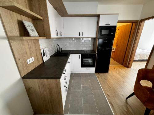 ブダペストにあるVH9 Apartmentsの小さなキッチン(白いキャビネット、黒の電化製品付)