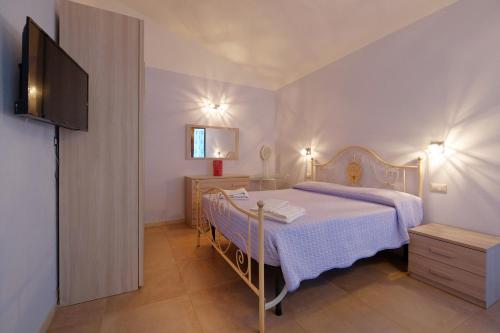 a bedroom with a bed and a television in it at CASA AZZURRA - BLUE HOUSE in Teulada