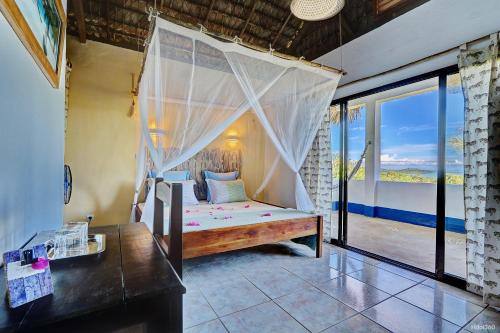 Schlafzimmer mit Himmelbett und Balkon in der Unterkunft Le Grand Bleu in Andilana