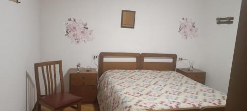 um quarto com uma cama e uma cadeira de madeira em Appartamento piario em Nasolino