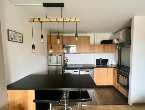 une cuisine avec une table noire et des chaises dans l'établissement Charmant T2 à 200m de la plage, location du samedi au samedi !, à Seignosse