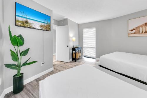 a white bedroom with a bed and a plant at Edgewater Tower 2-108-Gunners Paradise in Panama City Beach